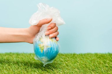 Küresel ısınma kavramının üzerinde yeşil ve mavi bir küre bulunan plastik poşet tutan kadın görüntüsü.
