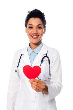 Steteskoplu Afro-Amerikan doktor, beyaza izole edilmiş dekoratif kırmızı kalp gösteriyor.