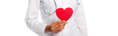 Beyaz panoramik karede izole edilmiş dekoratif kırmızı kalp gösteren steteskoplu Afro-Amerikan bir doktor.