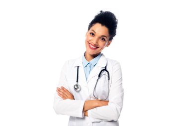Steteskoplu ve kollarını kavuşturmuş beyaz tenli, gülümseyen Afrikalı Amerikalı bir doktor.