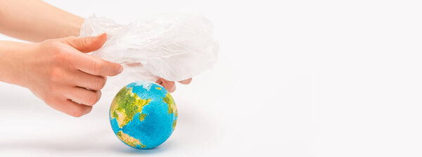 Cropped view of woman holding plastic bag above globe on white, global warming concept