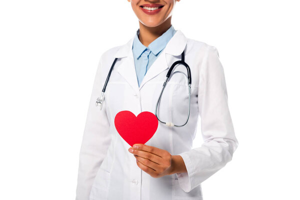 Cropped view of african american doctor with stethoscope showing decorative red heart isolated on white