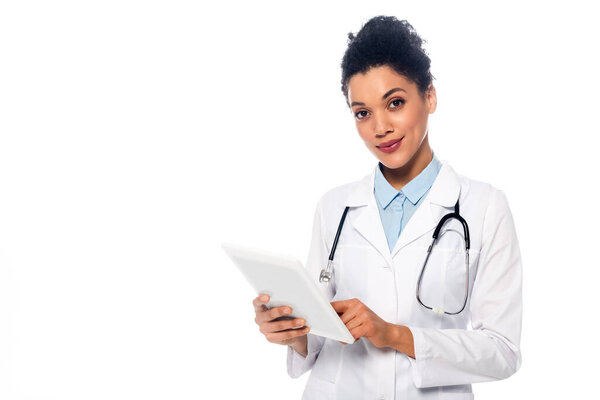 Фронтальный вид африканского врача со стетоскопом и цифровым планшетом, смотрящим на камеру, изолированную на белом
