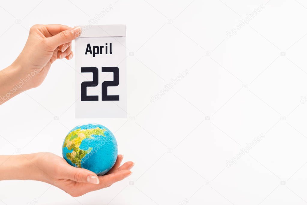 Cropped view of woman holding calendar with 22 april inscription and globe on white background, earth day concept