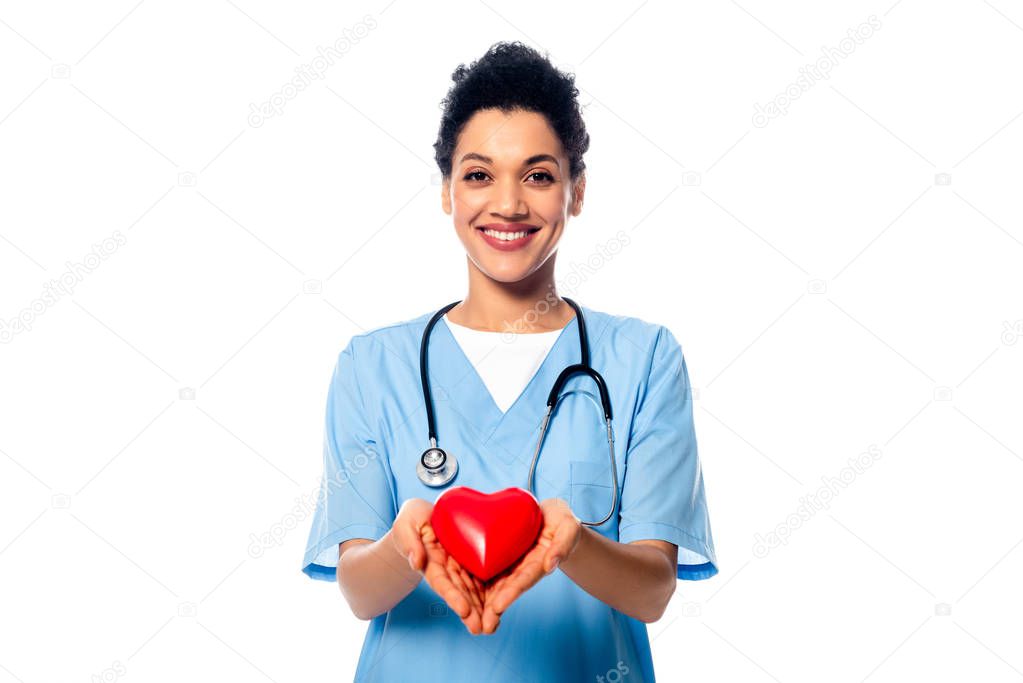 Front view of african american nurse with stethoscope showing decorative heart and smiling isolated on white