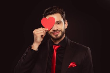 Siyah üzerine izole edilmiş kalp şeklinde kağıtlarla gözleri kaplayan yakışıklı bir adam.
