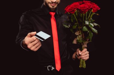 Zarif bir adamın elinde kredi kartı ve güller tutarken siyah kameraya baktığı görüntüler.