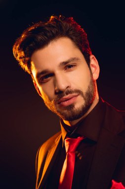 Resmi giysili ve kırmızı kravatlı yakışıklı siyah kameraya bakıyor.