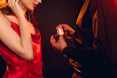 Siyah üzerine izole edilmiş zarif kız arkadaşına mücevher yüzüklü bir kutu veren adamın görüntüsü.