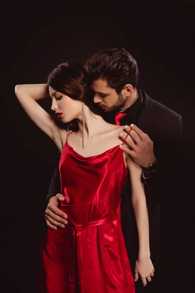 Yakışıklı Adam Sarılıyor Siyah Giyinmiş Güzel Bir Kadından Kırmızı Elbisesini — Stok fotoğraf