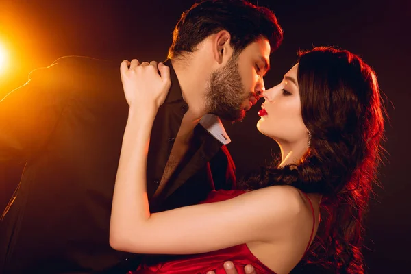 ハンサムな男接吻エレガントなガールフレンド上の黒背景にライティング — ストック写真