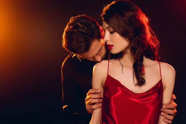 男人在漆黑的背景上亲吻优雅女友的肩膀 点着灯 — 图库照片