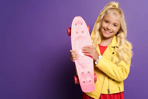 Sonriente Lindo Niño Sosteniendo Penny Board Sobre Fondo Púrpura — Foto de Stock