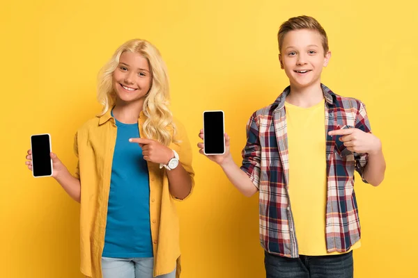 Crianças Sorridentes Apontando Com Dedos Para Smartphones Fundo Amarelo — Fotografia de Stock