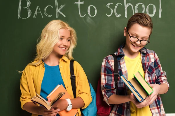 Smiling Schoolkids Holding Books Standing Chalkboard Back School Lettering — Stock Photo, Image