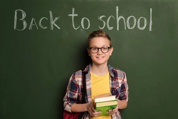 Scolaro Sorridente Con Libri Piedi Vicino Alla Lavagna Con Scritte — Foto Stock