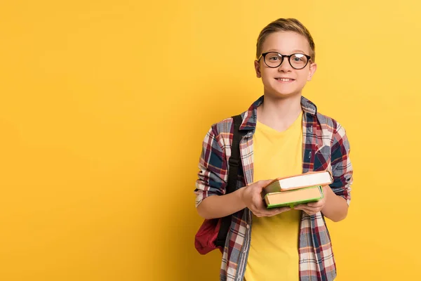 Leende Skolpojke Med Glasögon Hålla Böcker Gul Bakgrund — Stockfoto