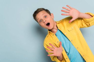 shocked and cute kid showing ten fingers on blue background  clipart