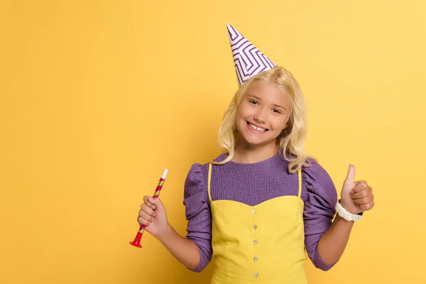 Smiling Kid Party Cap Holding Party Horn Showing Yellow Background — Stock Photo, Image