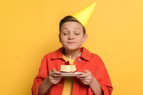 Uśmiechnięty Dzieciak Zamkniętymi Oczami Pragnący Trzymający Talerz Tortem Urodzinowym Żółtym — Zdjęcie stockowe