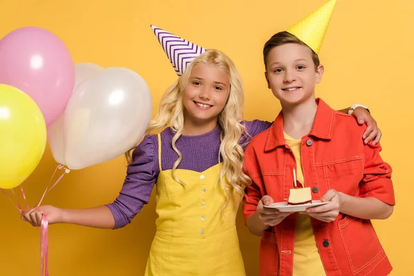 Χαμογελαστά Παιδιά Καπάκια Κόμμα Κρατώντας Μπαλόνια Και Πιάτο Τούρτα Γενεθλίων — Φωτογραφία Αρχείου