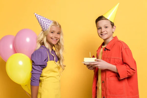 Smiling Kids Party Caps Holding Balloons Plate Birthday Cake Yellow — Stock Photo, Image