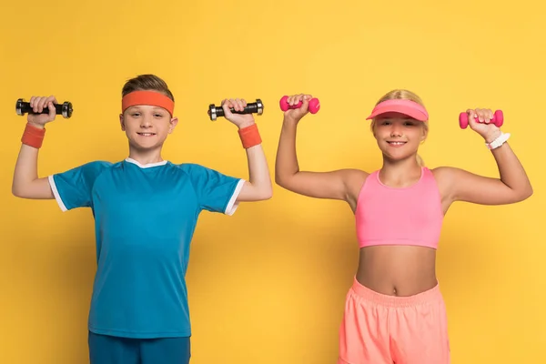 Crianças Sorridentes Treinamento Sportswear Com Halteres Fundo Amarelo — Fotografia de Stock