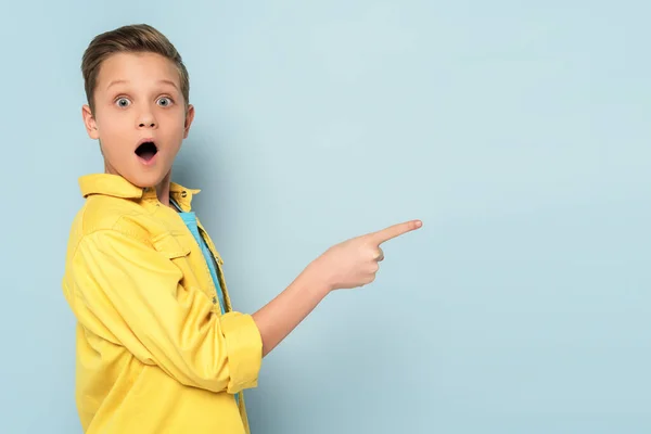 Chocado Lindo Niño Señalando Con Dedo Sobre Fondo Azul —  Fotos de Stock