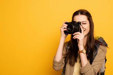 Sırt çantalı çekici bayan turist sarıya fotoğraf makinesi tutuyor. 