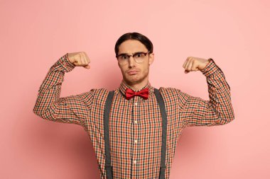 emotional male nerd in glasses showing muscles on pink clipart