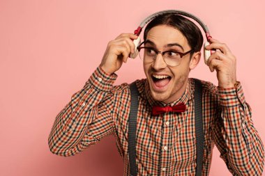 Gözlüklü heyecanlı erkek inek pembe kulaklıklı müzik dinliyor.