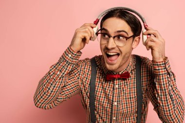 excited male nerd in eyeglasses listening music with headphones on pink clipart