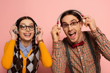 Gözlüklü bir çift heyecanlı inek pembe kulaklıklı müzik dinliyor.