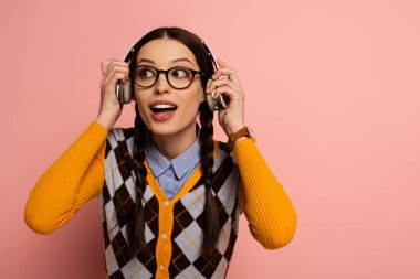 şaşırmış gözlüklü bayan inek pembe kulaklıklı müzik dinliyor.