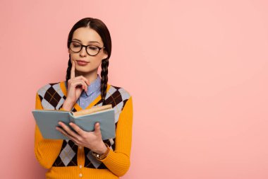 Gözlüklü düşünceli kadın inek pembe kitap okuyor.