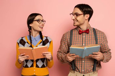 couple of smiling nerds in eyeglasses reading books on pink clipart