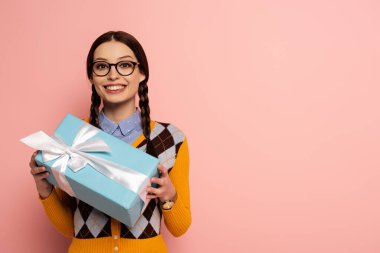 smiling female nerd in glasses holding gift box on pink clipart