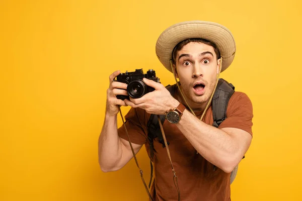 Turista Chocado Chapéu Com Mochila Segurando Câmera Fotográfica Amarelo — Fotografia de Stock