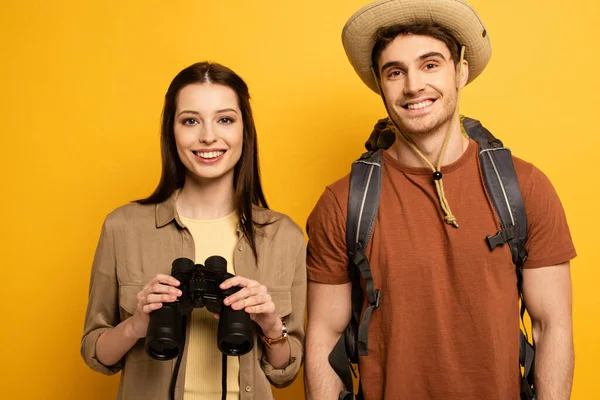 Pareja Viajeros Felices Con Mochila Binoculares Aislados Amarillo —  Fotos de Stock