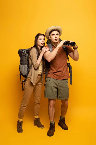 一对带着黄色背包和双筒望远镜的情绪化游客 — 图库照片