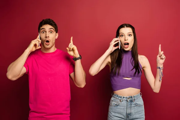 Shocked Couple Talking Smartphones While Pointing Red — Stock Photo, Image