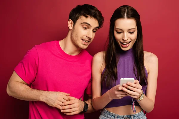 Schönes Lächelndes Paar Mit Smartphone Zusammen Auf Rot — Stockfoto