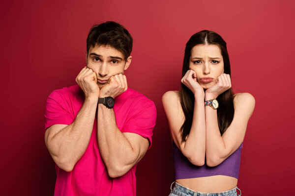 красивая расстроенная молодая пара жестом на красный
