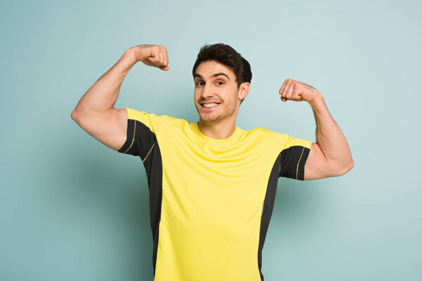 cheerful muscular sportsman in yellow t-shirt on blue