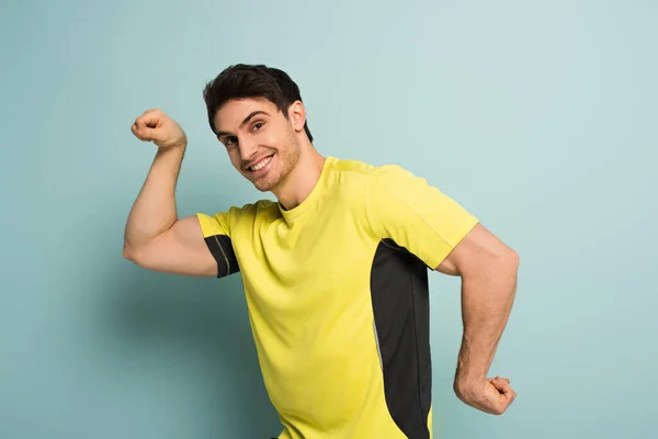 肌肉发达 面带微笑的运动员穿着蓝色的黄色T恤衫做手势 — 图库照片
