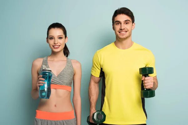 美丽的运动型夫妇 手里拿着哑铃和蓝色的运动型瓶装水 — 图库照片