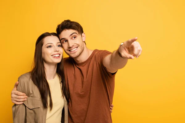 Casal Viajantes Bonitos Felizes Apontando Isolado Amarelo — Fotografia de Stock