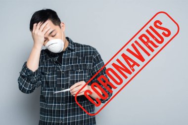 Solunum maskeli genç Asyalı adam termometreye bakıyor ve gri arka planda alnına dokunuyor, koronavirüs çizimi. 