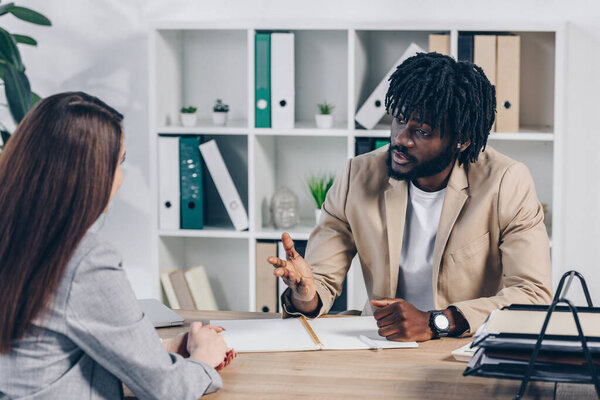African american recruiter talking with employee at table in office