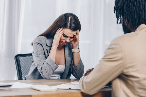 Селективный фокус африканского вербовщика с обеспокоенным и расстроенным сотрудником на собеседовании в офисе
